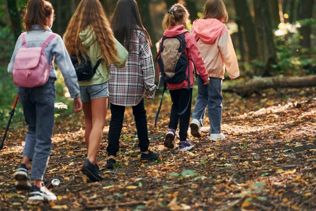 With touristic equipment. Kids in green forest at summer daytime together