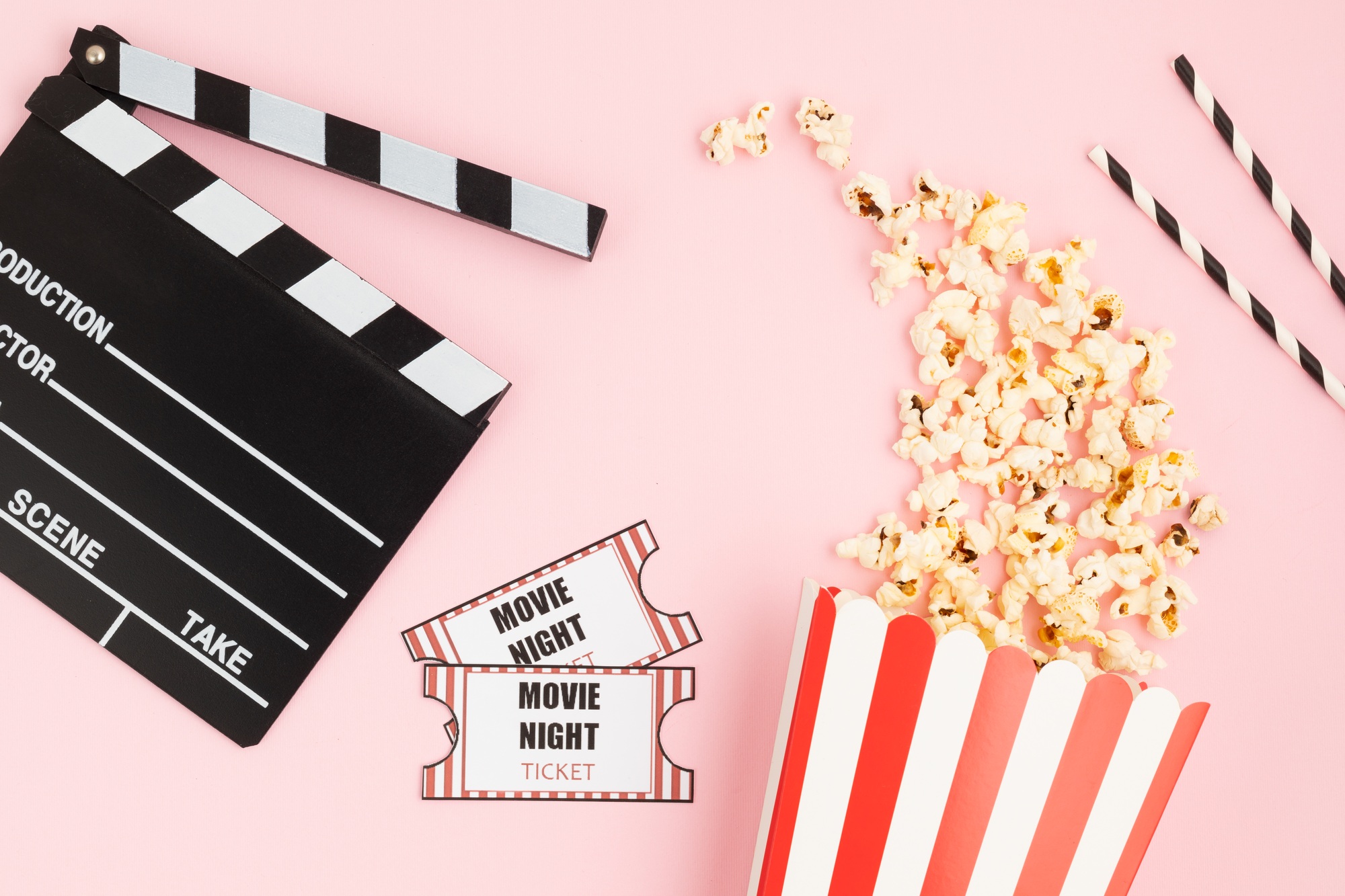 Movie clapperboard, tickets and popcorn over pink background. Movie night, home cinema, party